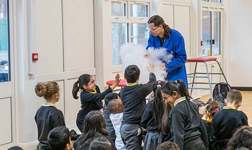 A researcher creating smoke for a group of primary school children