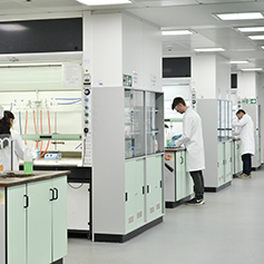 A number of researchers in lab coats working away in the lab