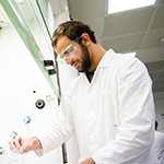 A male researcher in lab coat concentrating on his work