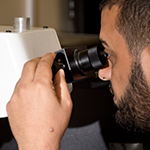A male researcher peering into a specialist microscope