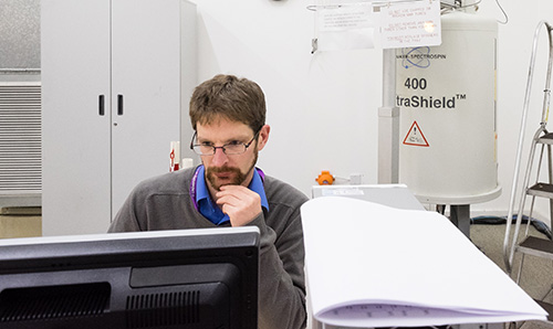 A male researcher using NMR equipment in the University