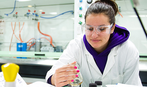 Female student examining a beaker during an experiment