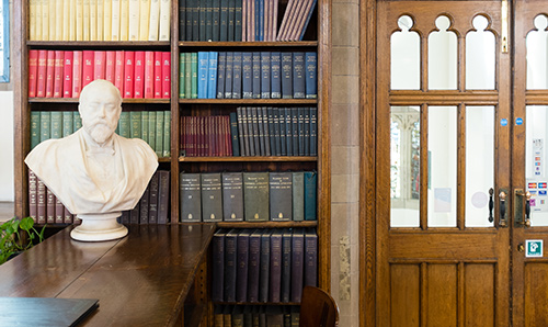 A bust of a man's head and shoulders in front of a shelf of library books