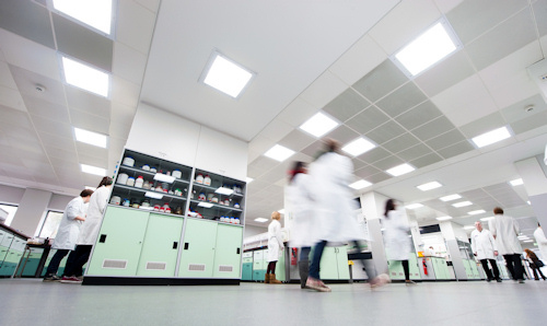 Chemistry students in white lab coats walking across the floor of a laboratory