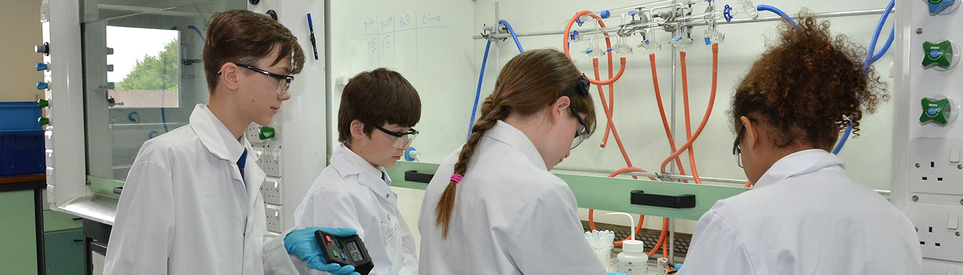 Four school children focusing on experiment in lab