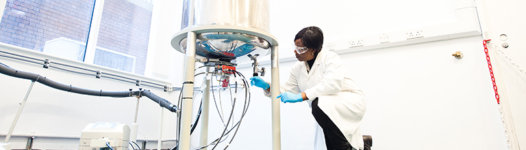 Female researcher wearing white lab coat adjusting apparatus