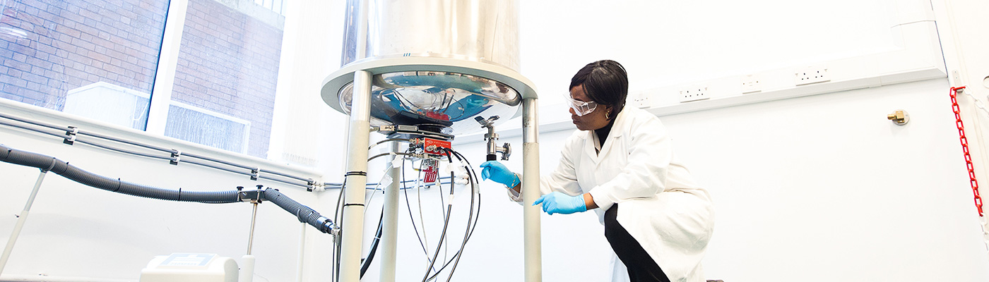 Researcher wearing white lab coat adjusting apparatus