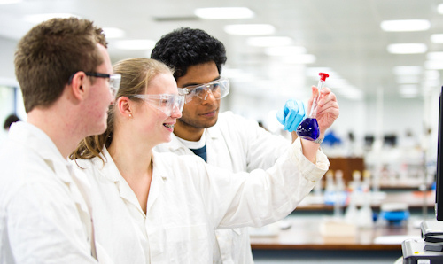 Three students looking at liquid in a test tube