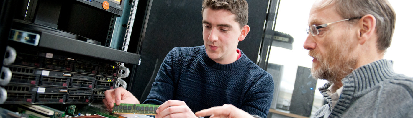 Student and lecturer installing memory chip into computer