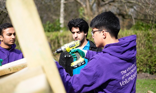 A male volunteer using a drill in the park