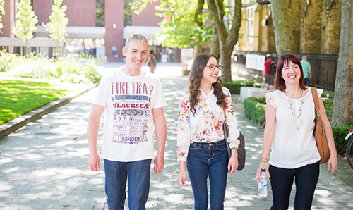 Parents and student smiling while walking through campus on open day