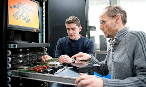 Student and lecturer installing memory chip into computer