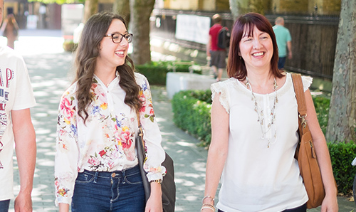 A mother and daughter smiling and walking on a University open day