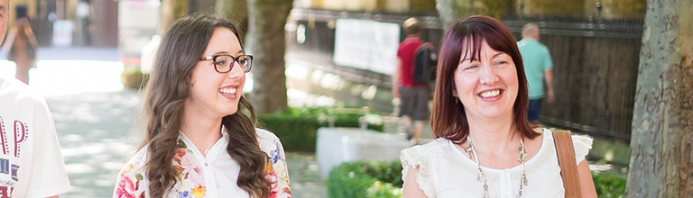 A mother and daughter walking and smiling on a University open day