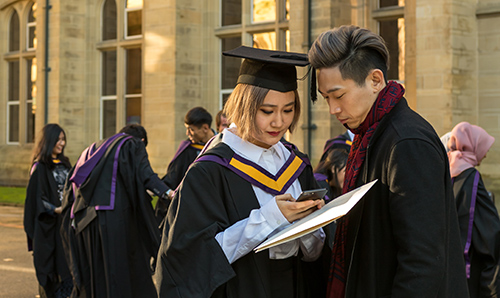 A student in her graduation gown stood with a partner